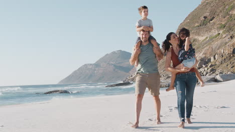 family walking along beautiful sandy beach on summer vacation