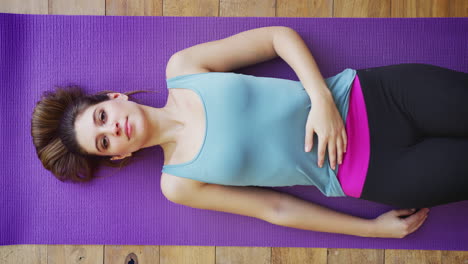 Retrato-Aéreo-De-Una-Mujer-Joven-Haciendo-Yoga-En-Un-Piso-De-Madera-Y-Riendo