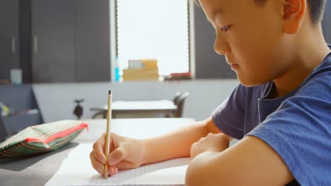 학교의 교실에서 책상에서 공부하는 주의 깊은 아시아 학교 소년의 측면 뷰 4k