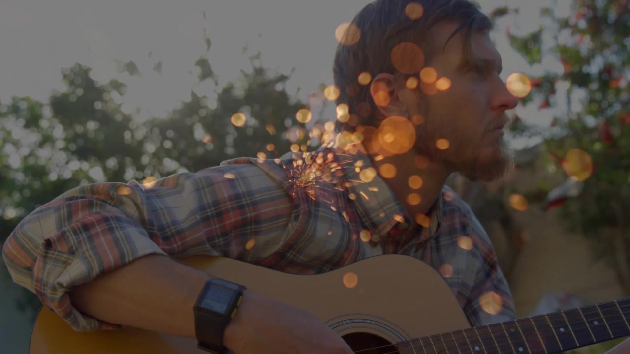 Voksende bokeh-overlay, mand begynder at klimpre på guitar i haven, med pulserende effekt nær skulderen for at indikere musik.