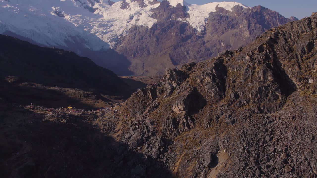 el avión no tripulado de la mañana captura a los ciudadanos subiendo a pie a la montaña huaytapallana para el festival tayta shanti, revelando montañas nevadas en el fondo