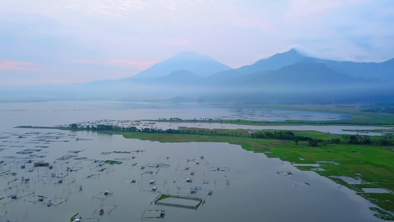 vista aérea del hermoso paisaje tropical con vistas a muchas jaulas de peces en el enorme lago y montaña en el fondo - lago rawa pening, indonesia