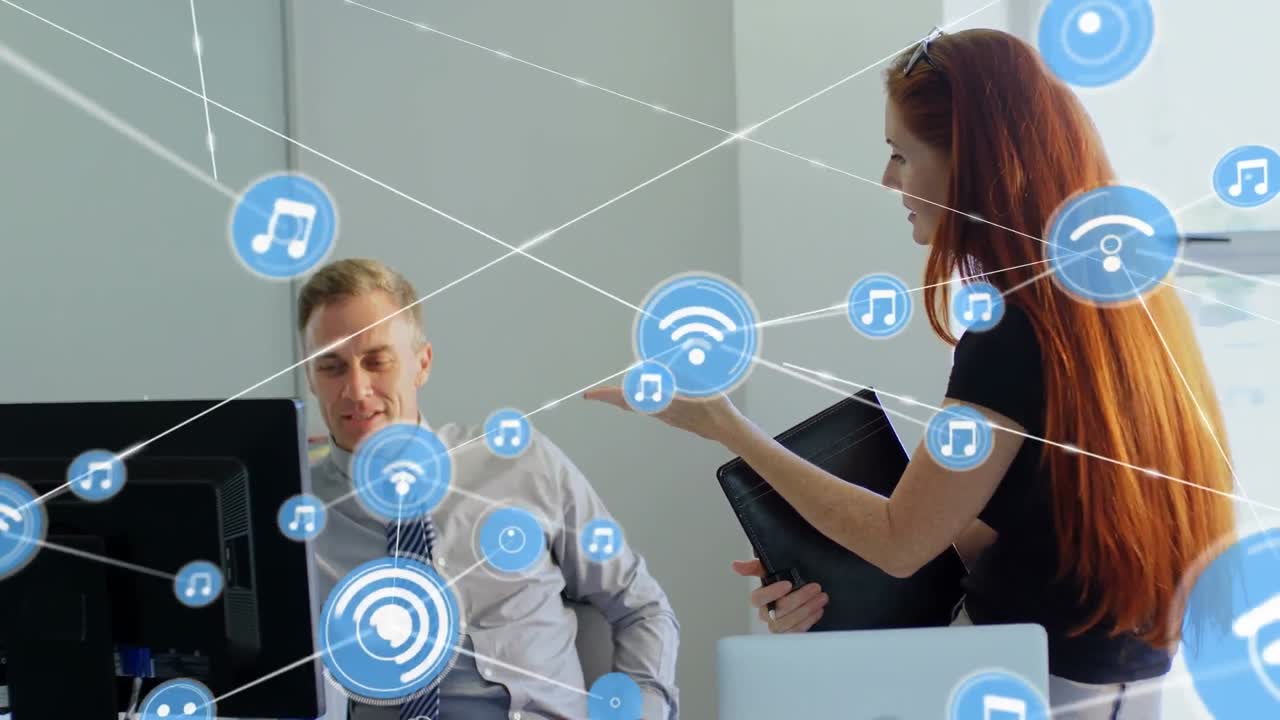 анимация сети икон над кавказским бизнесменом и бизнесменкой, обсуждающими в офисе.