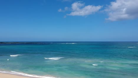 位於海灘旁邊的海灘, 位於 oahu 北岸的海灘上, 有藍天, 青<unk>色, 太平洋, 棕<unk>樹, 和一些白雲.