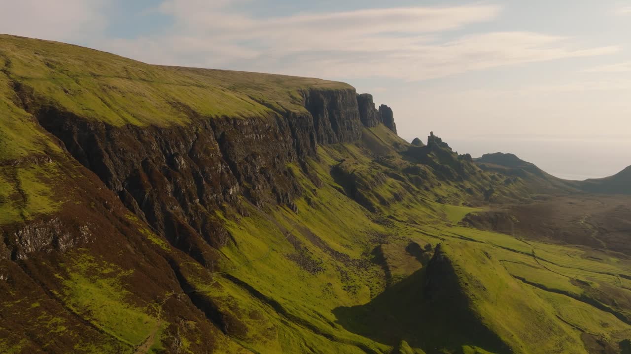 Aerial drone footage of the dramatic mountain landscapes on the Isle of Skye, Scotland. Sweeping panoramic views of majestic peaks, green valleys, and wild nature