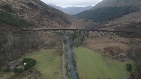 the historic glenfinnan viaduct in scotland, surrounded by rugged landscapes and greenery, aerial view