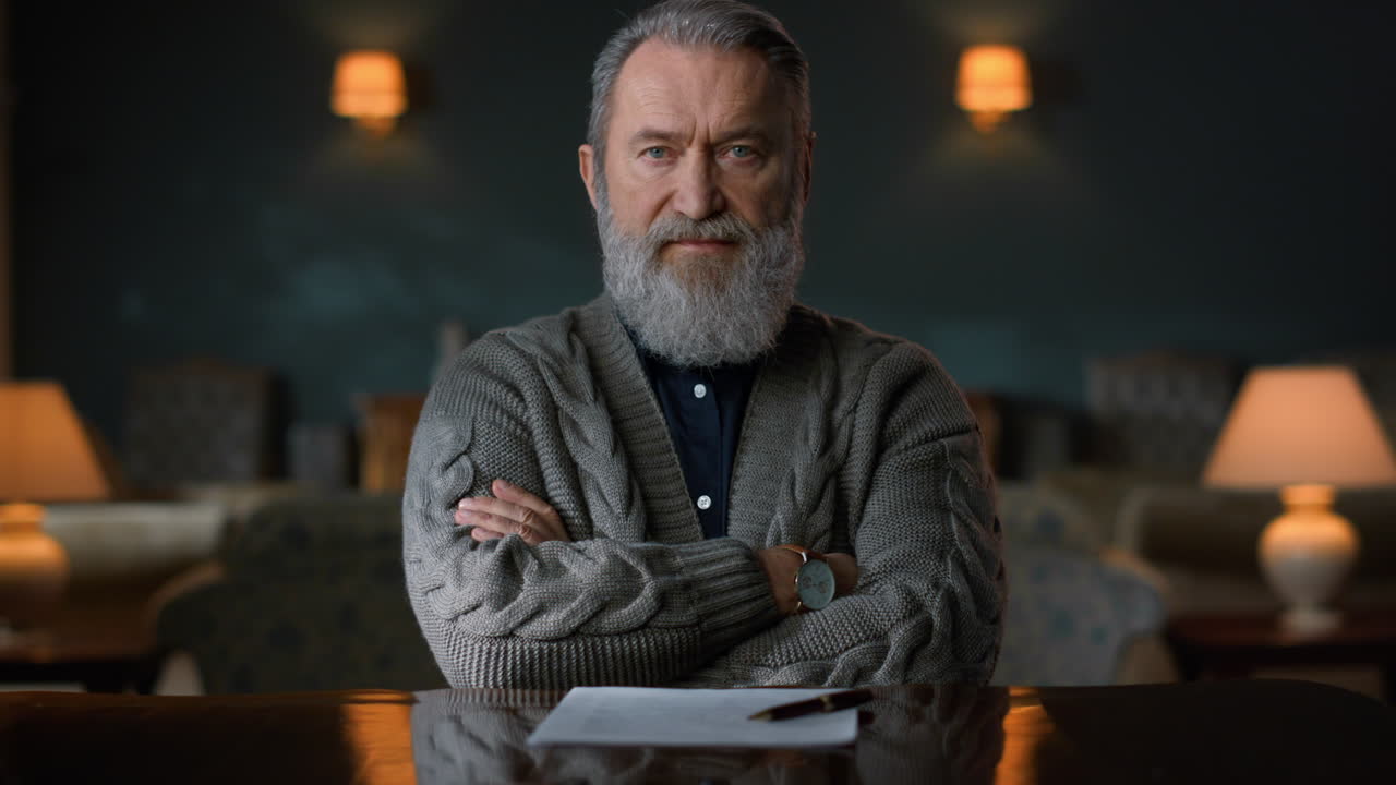 고전적 인 인테리어 의 노인 초상화. 심각 한 노인 이 집 에서 카메라 를 포즈 하고 있다