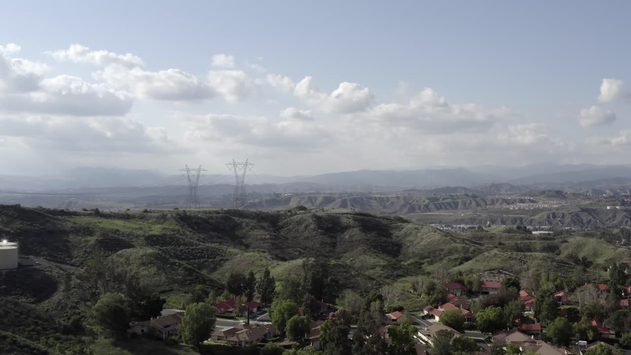 Aerial view over neighborhood of house with Power lines, mountains and clouds in distance