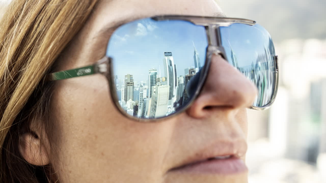 Close-up of Woman's Face with City Skyline Reflected in Sunglasses