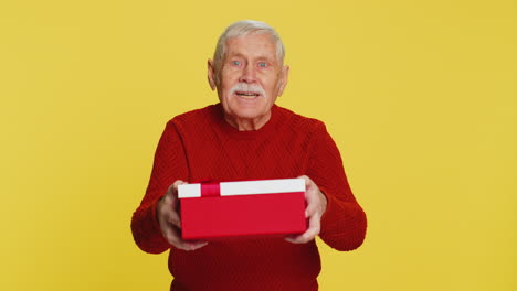 smiling senior man presenting birthday gift present box stretches out hands promotion discount sale