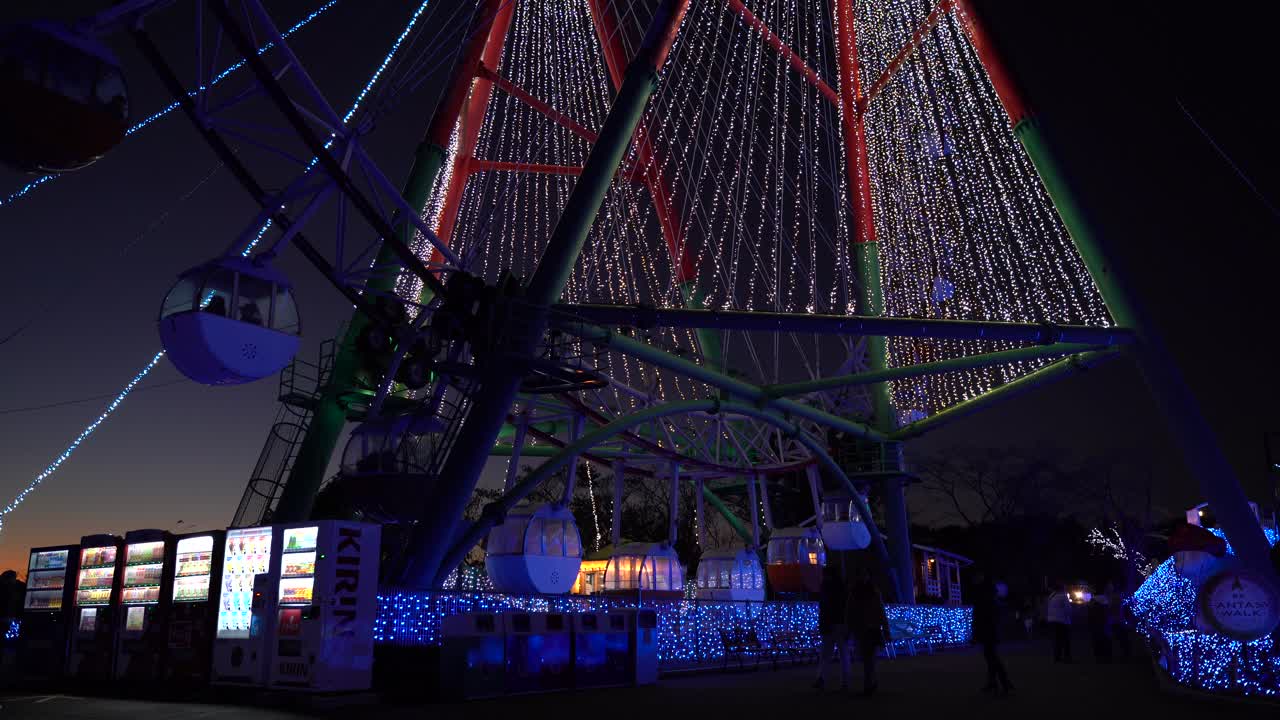 Beautiful Illuminations Near Ferris Wheel In An Amusement Park In Japan With Sunset Sky In The Background - Wide Shot