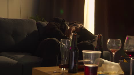 Man-Lying-Passed-Out-On-Sofa-After-Drinking-Alcohol-At-House-Party-Suffering-With-Hangover