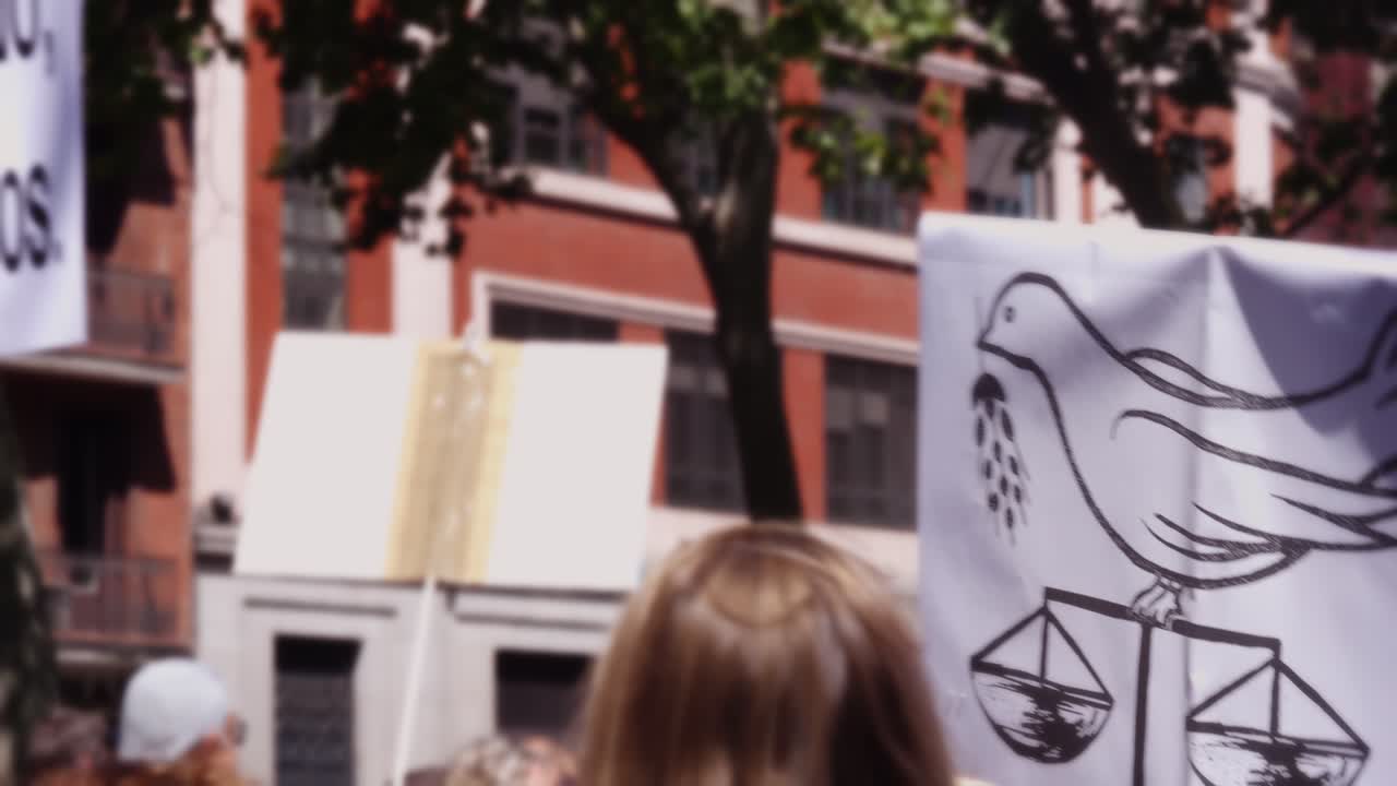 Manifestante che tiene un cartello con una colomba e la bilancia della giustizia