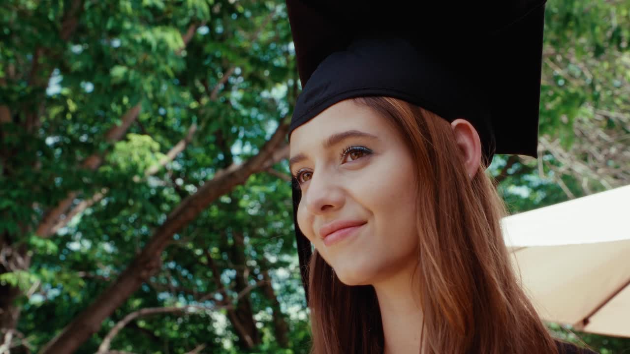 A female graduate student looks off camera thoughtfully with tree canopy overhead.
