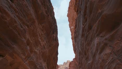 Looking-up-in-the-Siq-canyon-at-The-Treasury-at-Petra,-historic-UNESCO-heritage-site-carved-into-sandstone-in-Jordan