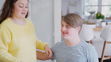 una pareja joven con síndrome de down celebra su cumpleaños en casa con pastel.