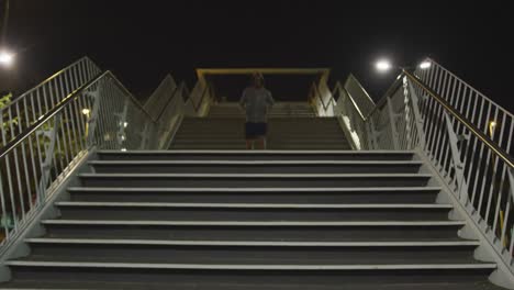 hombre con capucha caucásico haciendo deporte en una calle por la noche