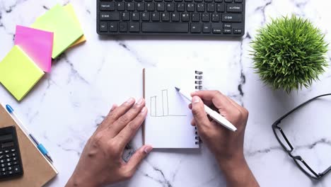 persona dibujando un gráfico en un cuaderno