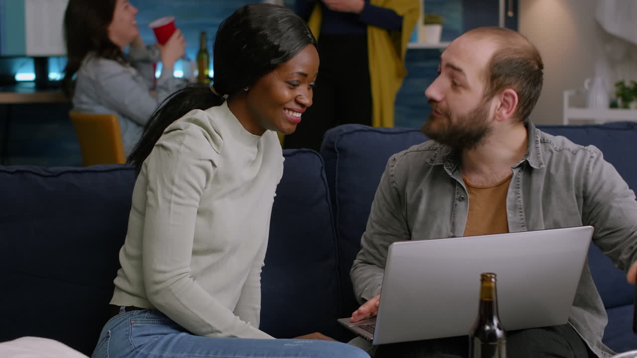 amigos multirraciales socializando mientras ven videos en línea en la computadora portátil