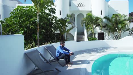 young businessman is walking and working on tablet near the pool in warm country