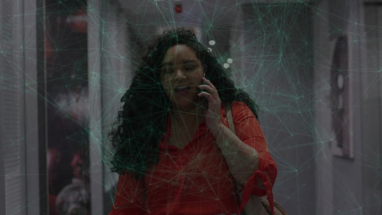 Donna che risponde a una chiamata di lavoro mentre cammina in corridoio, con un overlay web verde che mappa i dati e l'espressione che cambia.