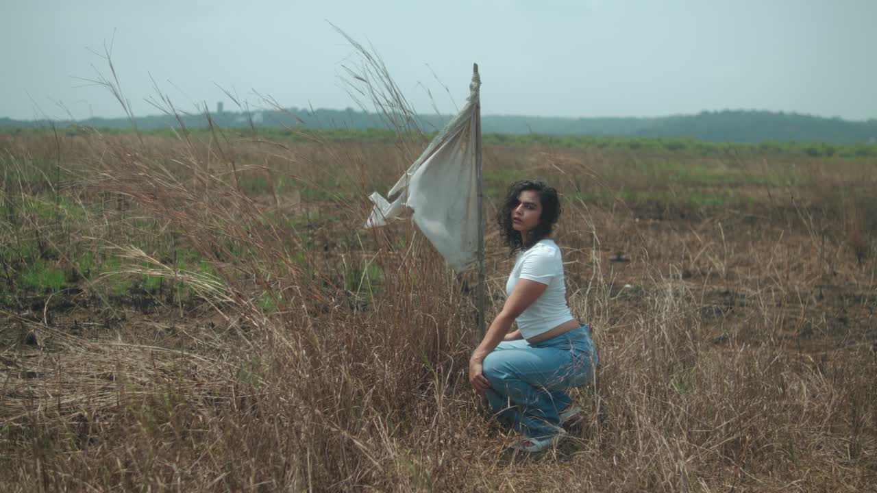 Woman in field with fabric, contemplating nature on a cloudy day