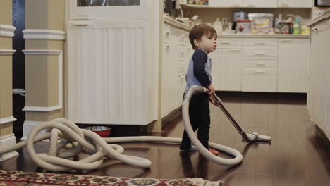 cute asian two-year-old toddler trying to vacuum in a room