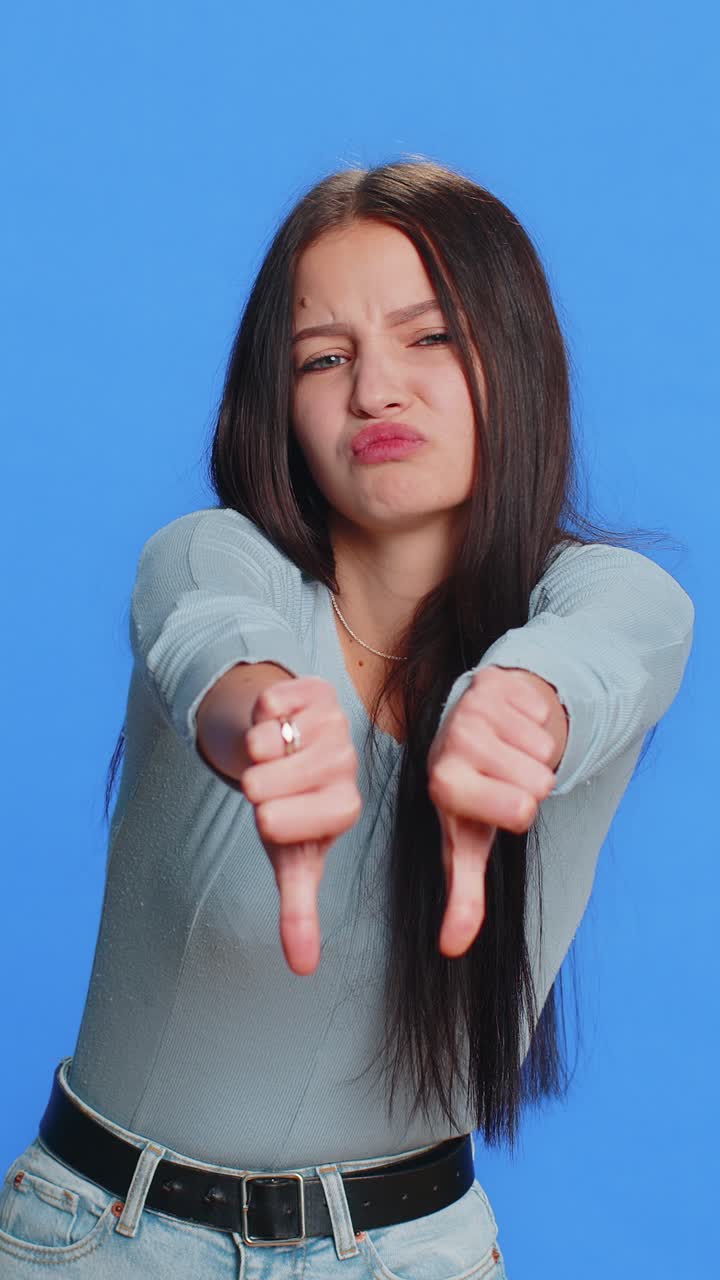 Upset attractive young woman girl showing thumbs down sign gesture disapproval dissatisfied dislike