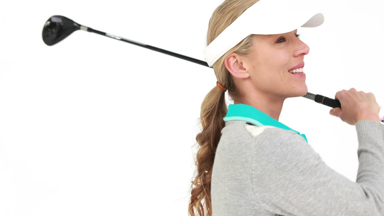 골프 선수 가 공 을 치고 카메라 에 미소 짓고 있다