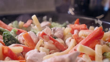 primer plano: pollo y verduras al vapor en una sartén sobre una estufa caliente