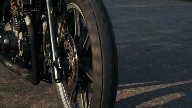 Close Up view of a moving firewheel of the motorcycle. Unrecognizable person riding the motorcycle on a country road