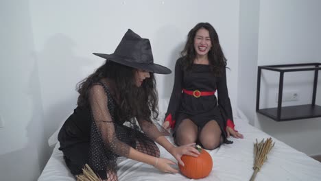 two witches playing with a pumpkin on a bed