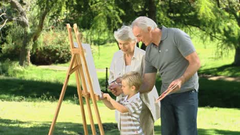 boy painting a canvas with his grandparents