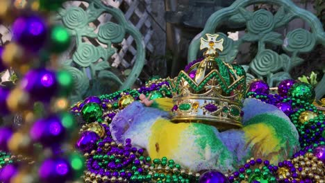 strings-of-beads-framing-Mardi-Gras-king-cake-with-crown-and-tiny-baby-surrounded-by-colorful-beads-and-dappled-sunlight