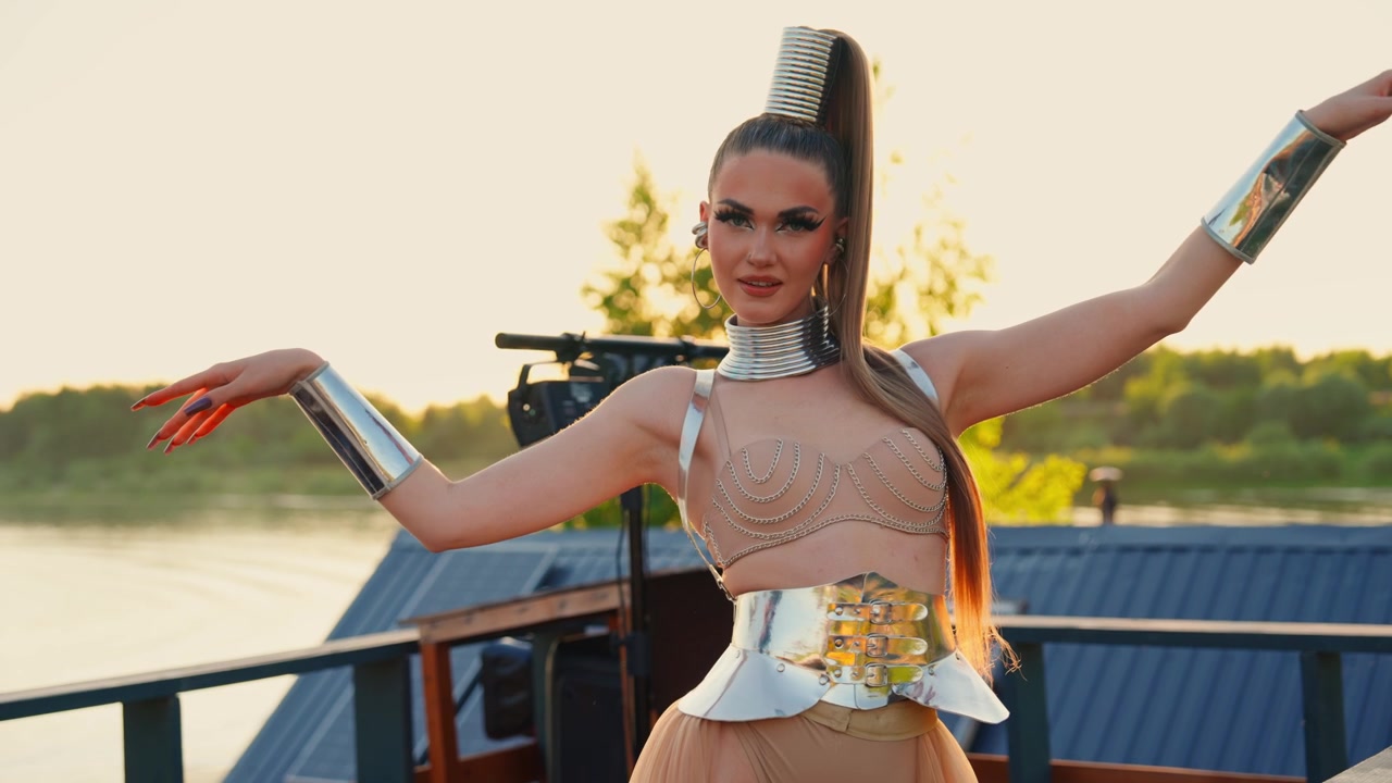 Donna alla moda con un outfit metallico futuristico che posa all'aperto al tramonto