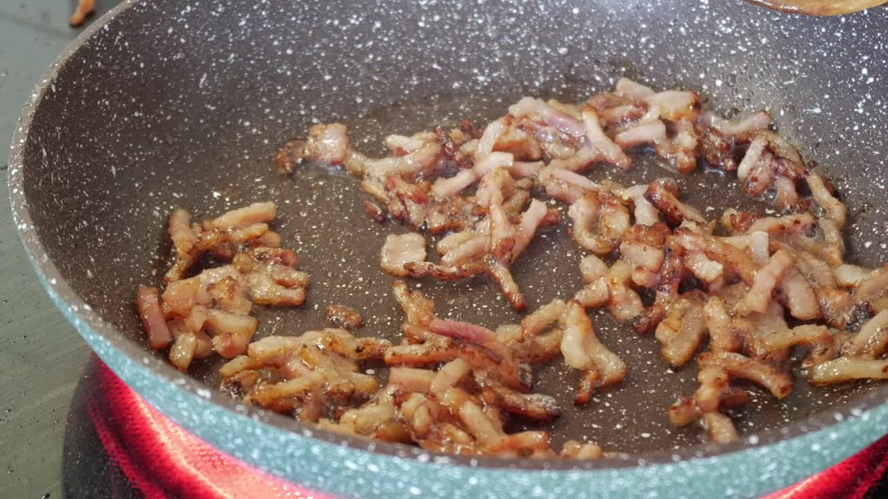 Crispy bacon frying in a pan, sizzling and cooking in hot oil with a golden hue