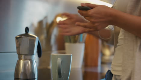 mujer hermosa usando tecnología de teléfono inteligente haciendo café por la mañana