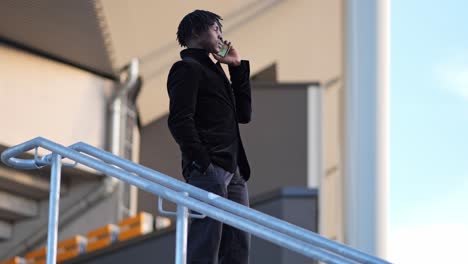 Orbit-shot-of-an-African-Businessman-Under-a-Modern-Building-Roof-in-an-Outdoor-Phone-Call