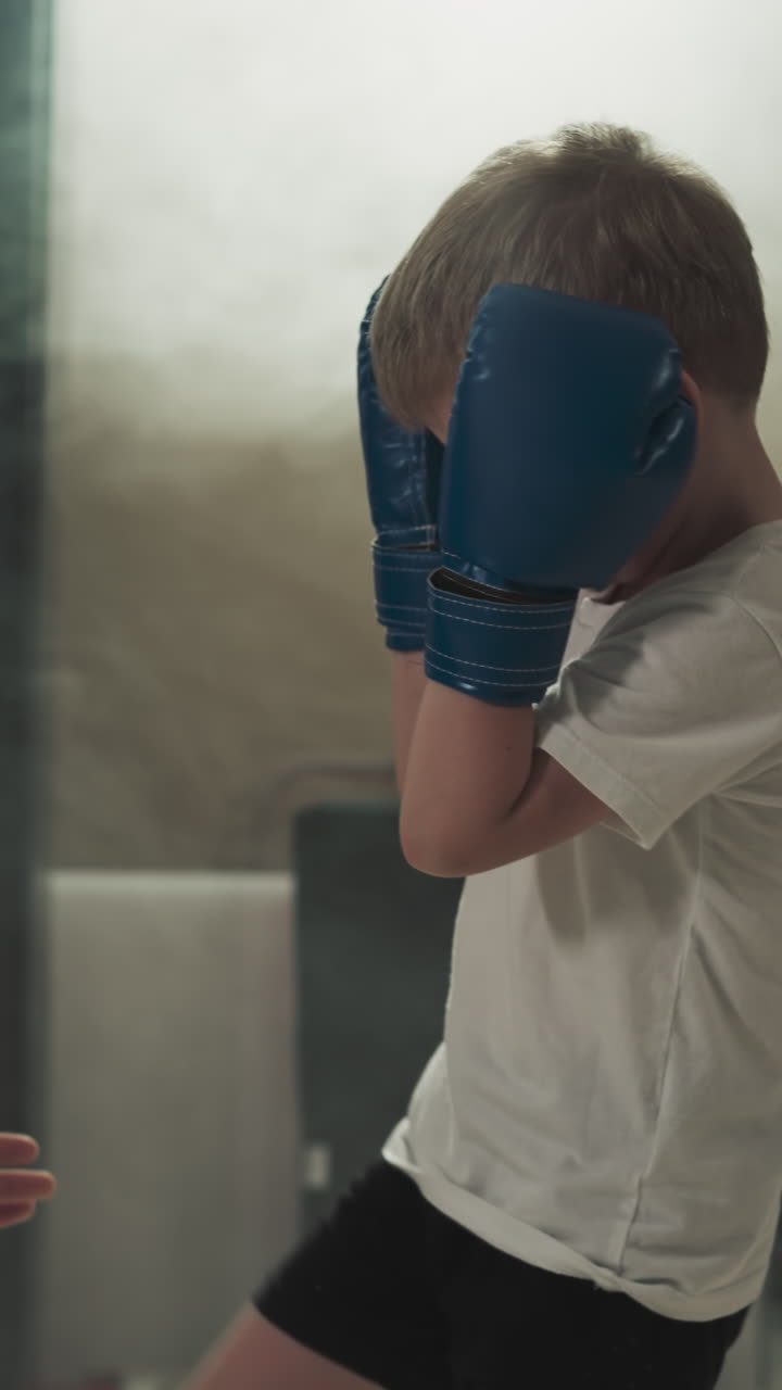 el niño hace patadas con el instructor en el gimnasio de artes marciales. el joven entrenador lleva a cabo una lección de kickboxing con un niño en el centro deportivo en cámara lenta. vida saludable