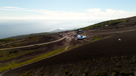 aerial view of osorno volcano in chile showing rugged terrain, winding road, remote base station and the pacific in the distance on a clear day