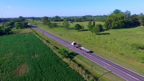 A-freight-train-on-the-circunvalar-santa-fe-route-with-green-fields-in-daylight,-aerial-view