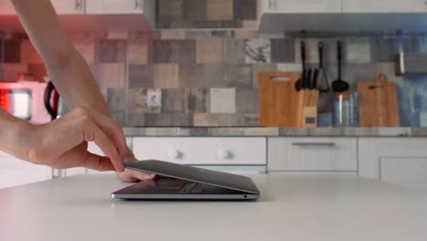 person opening a laptop in a kitchen