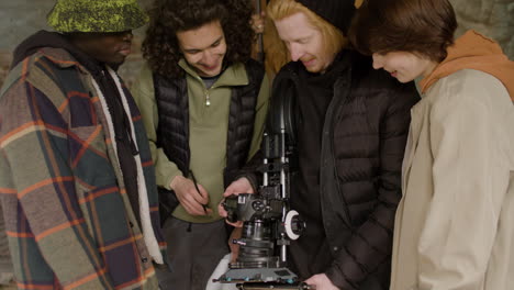 close up view of a production team and cameraman laughing while reviewing a scene in a camera in a ruined building