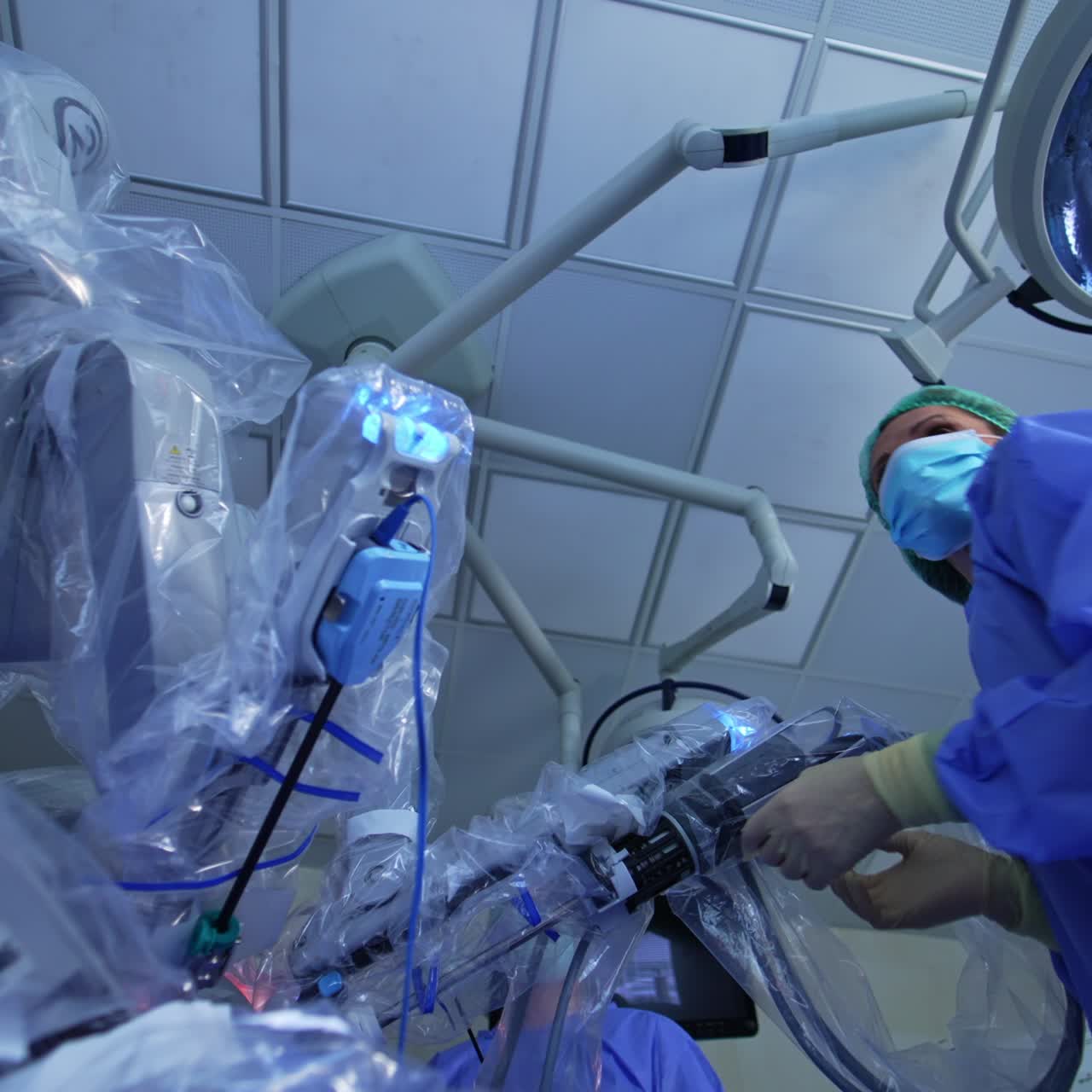 Female doctor comes up to the robotic equipment. Medic fitting the manipulator active arm looking at the screen. Low angle view