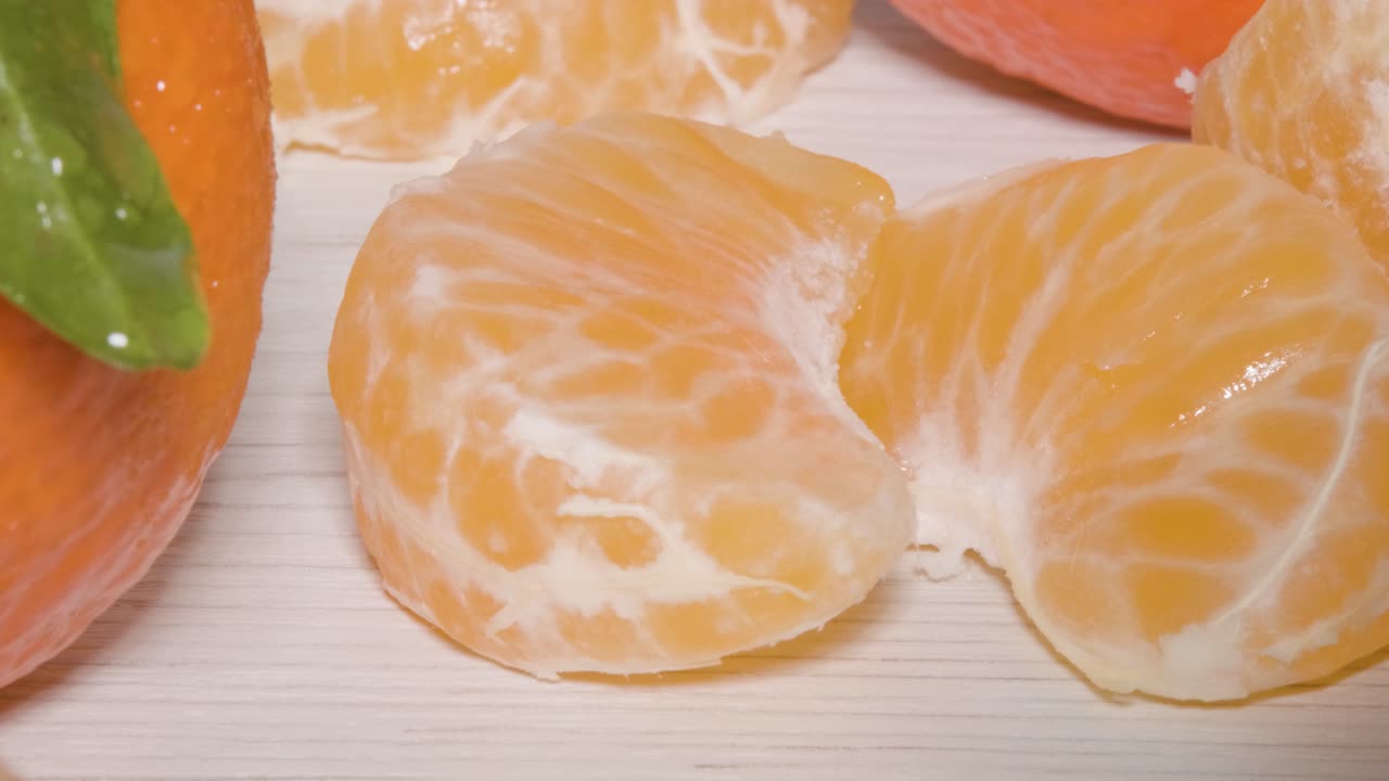 테이블에 있는 만다린 오렌지의 2개 세그먼트, 비타민, 영양소 및 미네랄로 가득 찬 신선한 건강한 감귤류 과일을 드러내는 매크로 샷을 닫습니다.