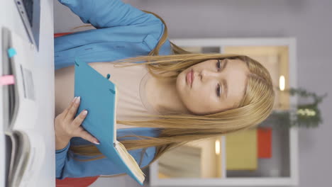 Vertical-video-of-Female-student-working-between-paper-and-laptop.