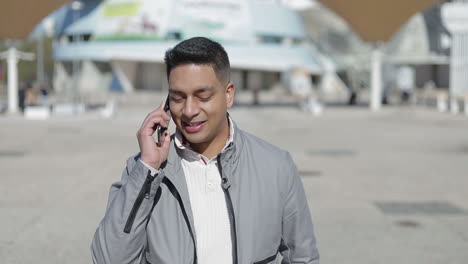 Relaxed-smiling-handsome-guy-talking-on-phone-during-stroll