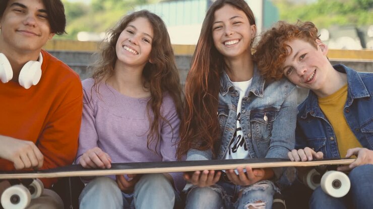 Um grupo de amigos adolescentes, com duas meninas e dois meninos, olhando diretamente para a câmera e sorrindo 2