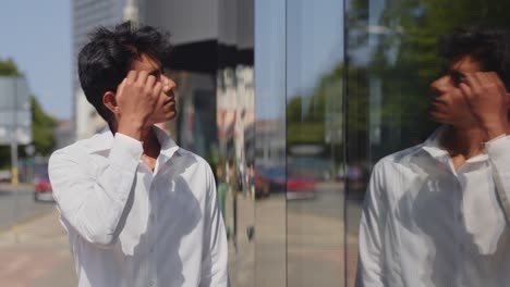 apuesto joven modelo masculino arreglando el cabello mirando en el reflejo de la ventana