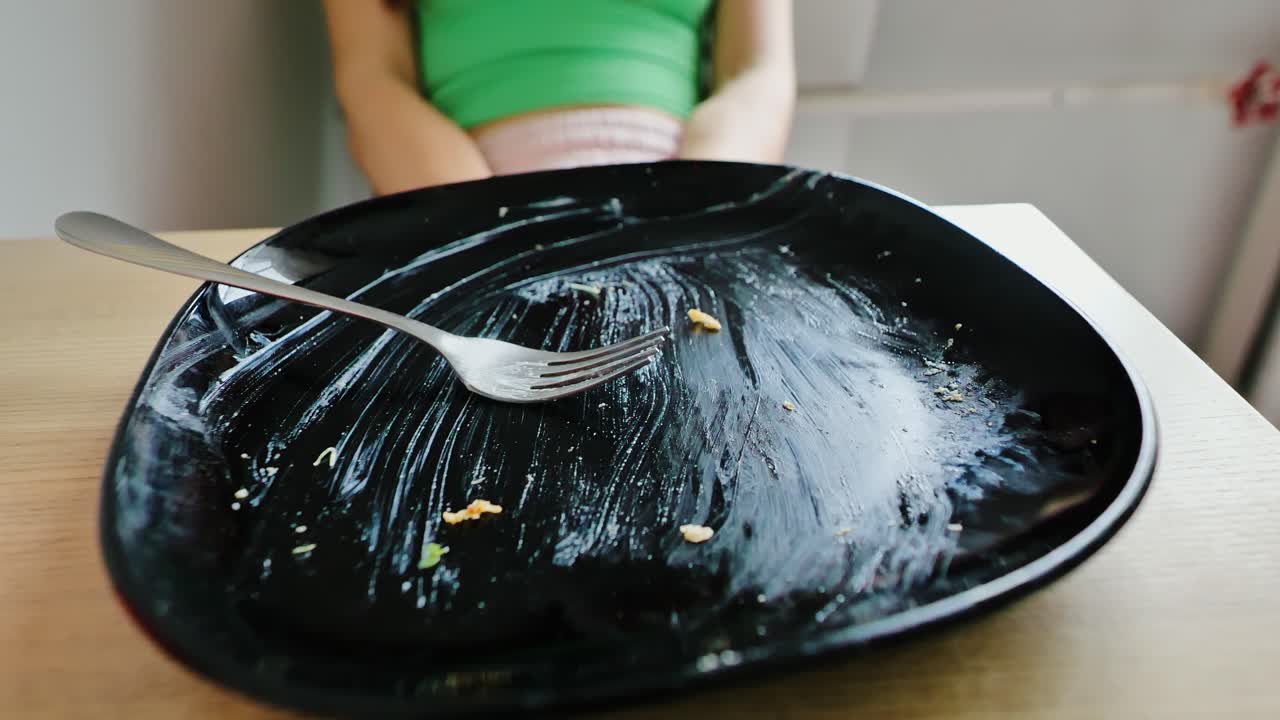 Conceptual shot, overeating regret with clean plate and woman in background